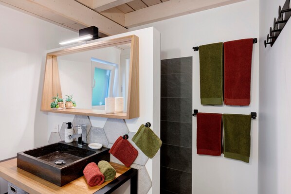 Un baño con espejo, lavabo y toallero.