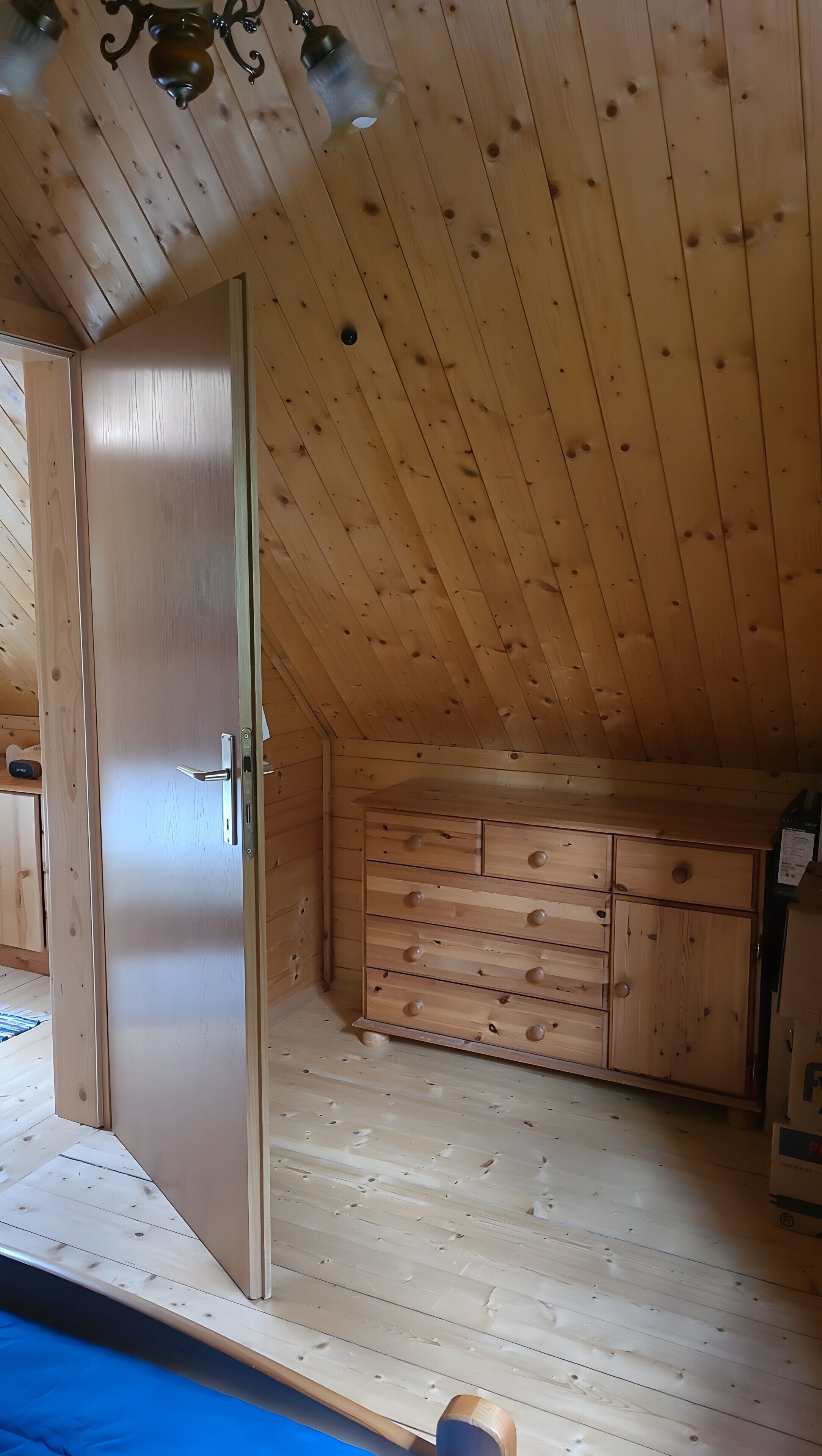 Una habitación con techo de madera, puerta corrediza y un armario empotrado con cajones.