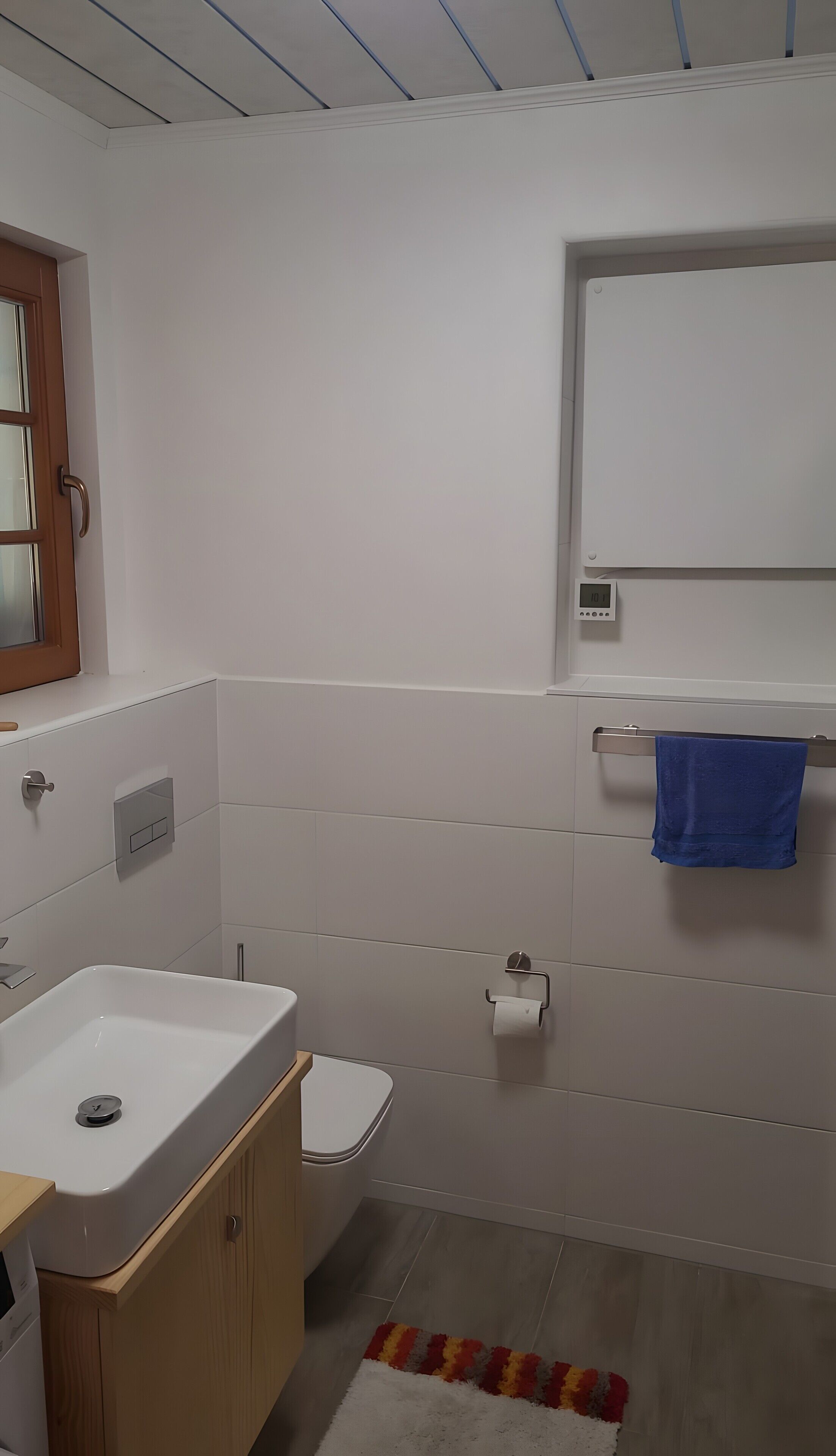 Un bagno moderno con lavandino, vaso e specchio sopra il lavandino bianchi.