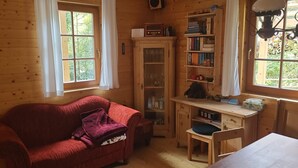 A cozy room with a red sofa, a wooden cabinet with glass doors, and a bookshelf.