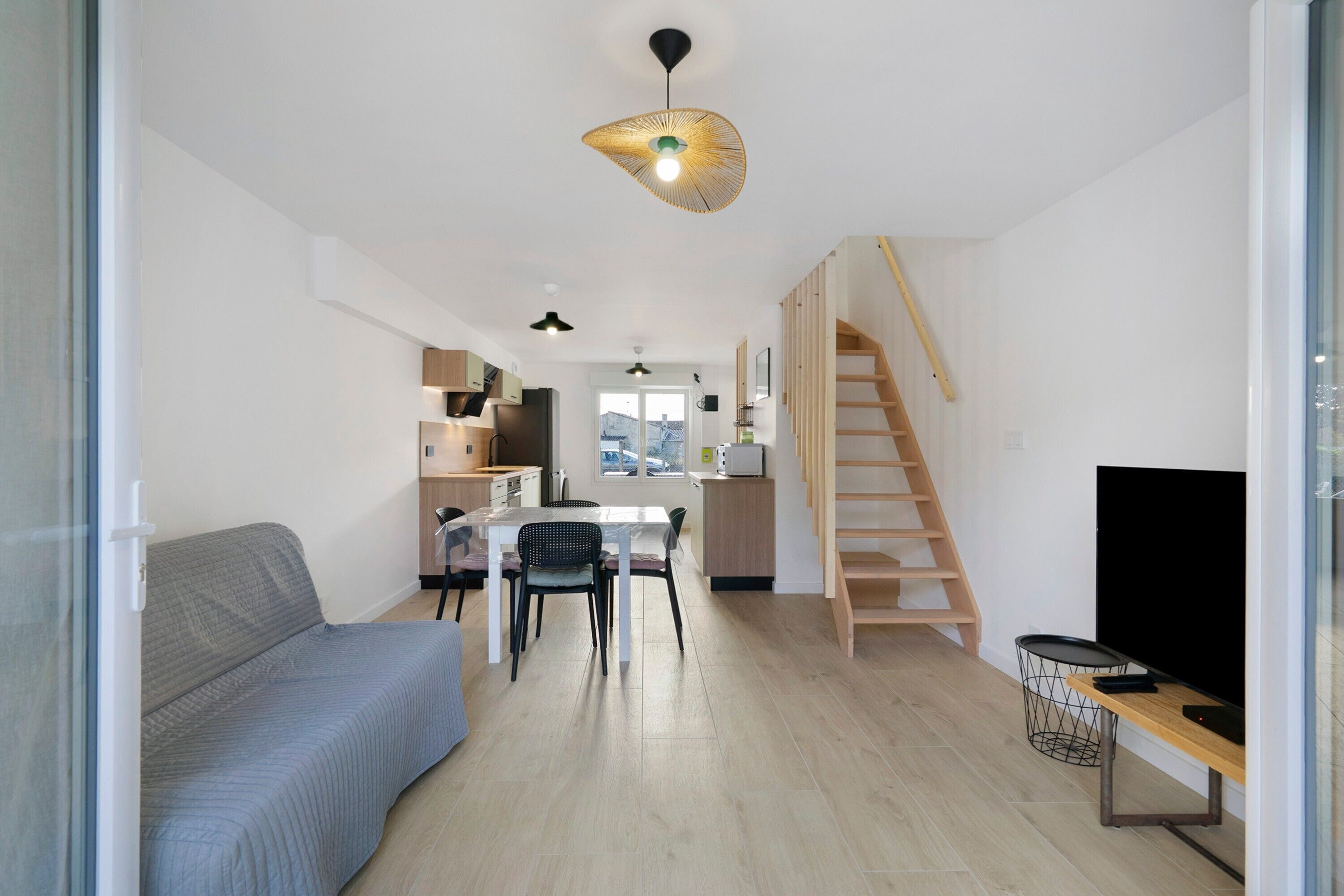 Un espace de vie moderne comprenant un canapé, une table à manger, des chaises, un téléviseur et un escalier.