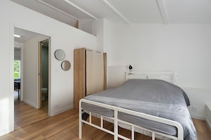 A bedroom with a bed, a wardrobe, and a mirror.
