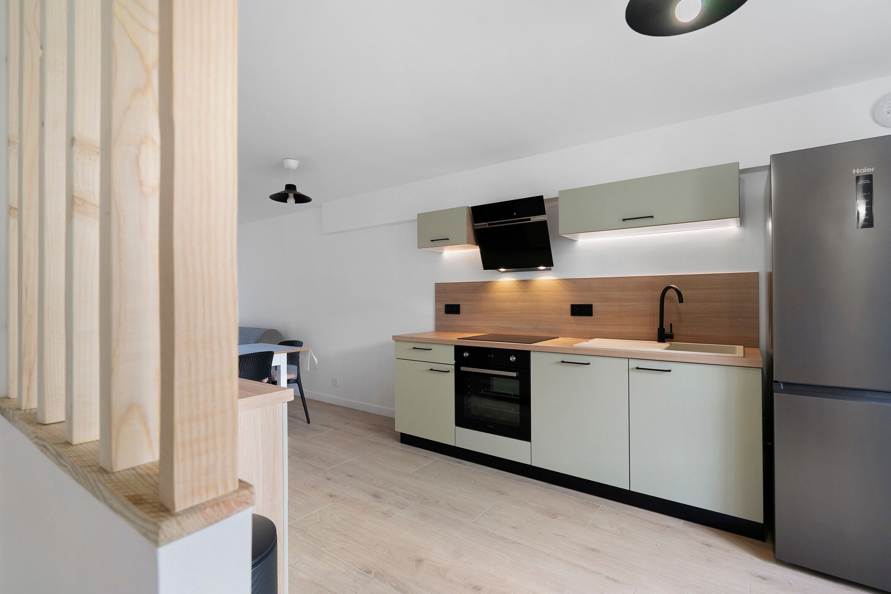 Une cuisine moderne dotée d’un four encastré, d’un réfrigérateur en acier inoxydable et d’un plan de travail en bois.