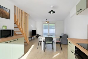 A modern kitchen with a dining area, wooden staircase, and a ceiling fan.