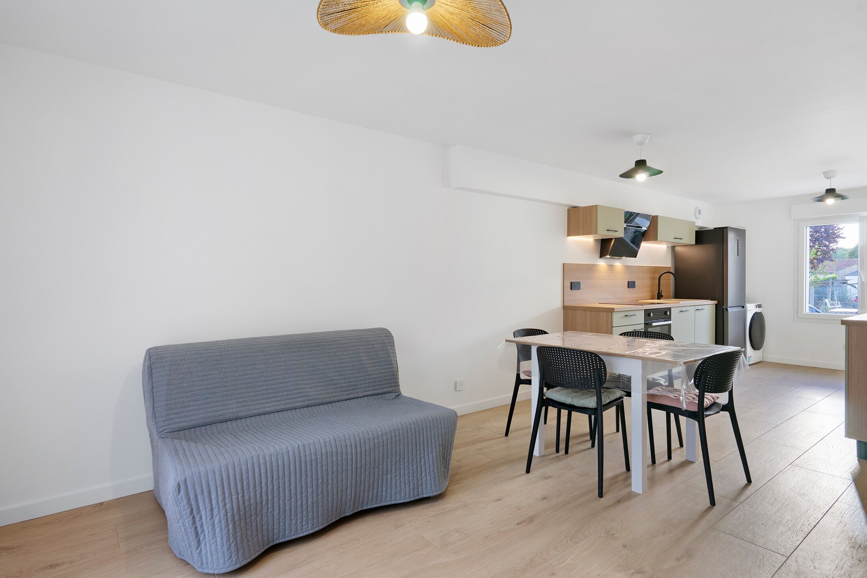 Ett kompakt bostadsutrymme med ett litet kök, en matplats och en soffa.