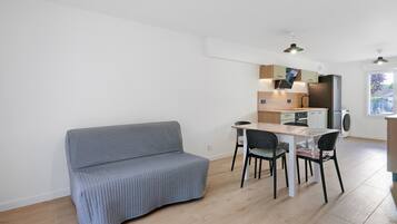 Ett kompakt bostadsutrymme med ett litet kök, en matplats och en soffa.