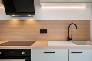 A modern kitchen with a black faucet, a built-in oven, and a light-colored countertop.
