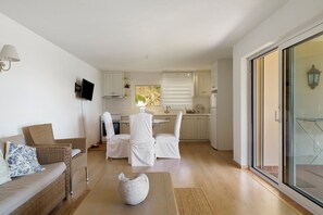 Ein geräumiger Wohnbereich mit einer Couch, Sesseln und einer dekorativen Vase.