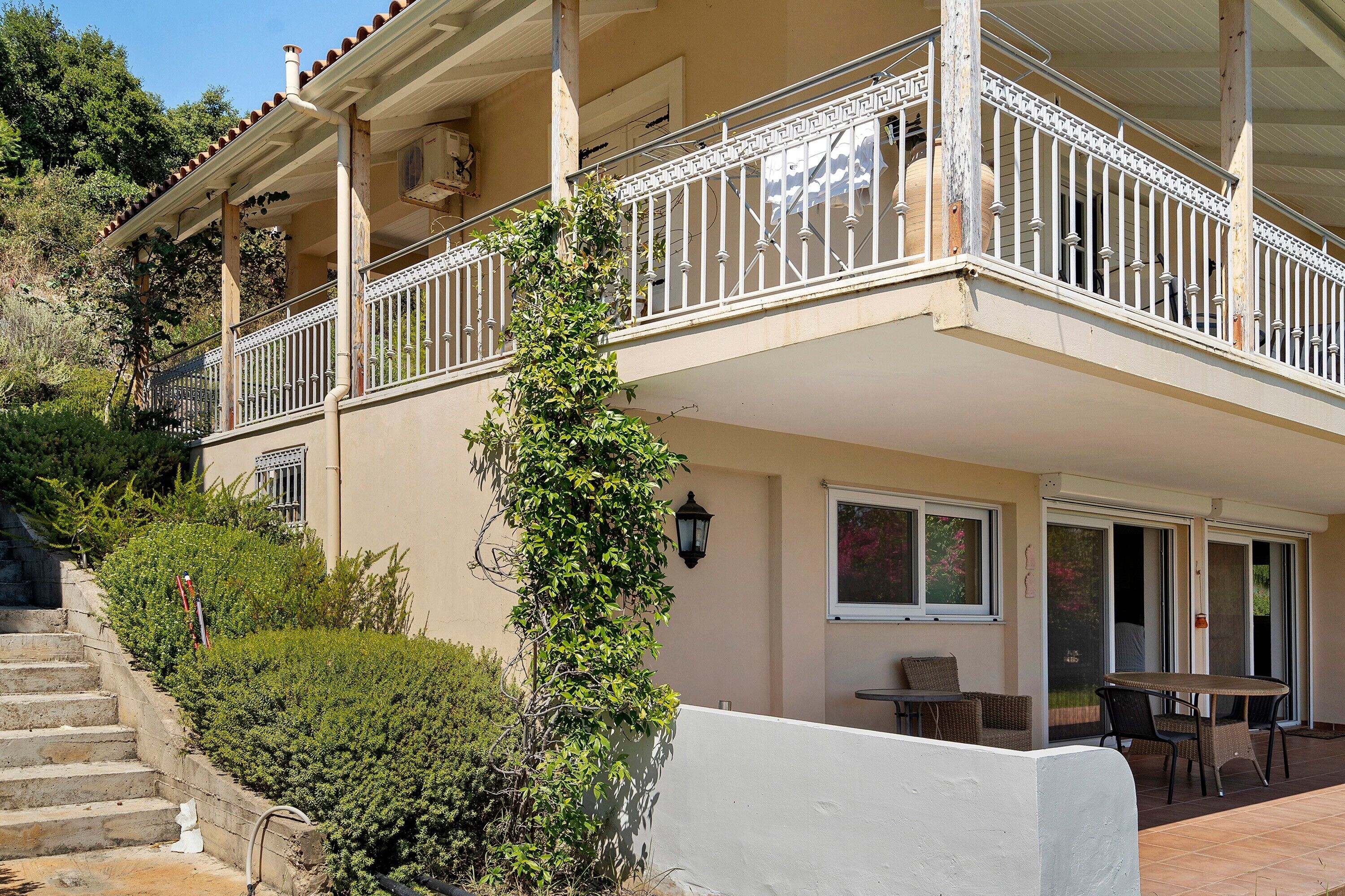 A two-story building with a balcony, a staircase, and a patio area with outdoor furniture.