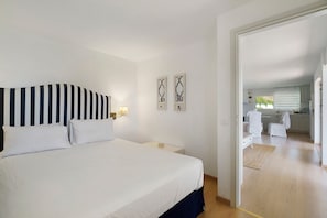 A hotel room with a bed, a nightstand, a wall-mounted lamp, and two decorative mirrors. - Holiday Home 'Evans Garden Suite' (Nikiana)