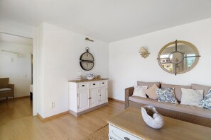 A living room with a sofa, a round mirror, a wall clock, and a cabinet. - Holiday Home 'Evans Garden Suite' (Nikiana)