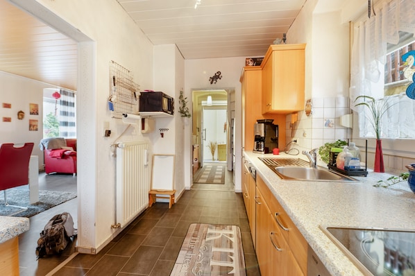 A modern kitchen with a central island, wooden cabinets, and a view into the dining area.
