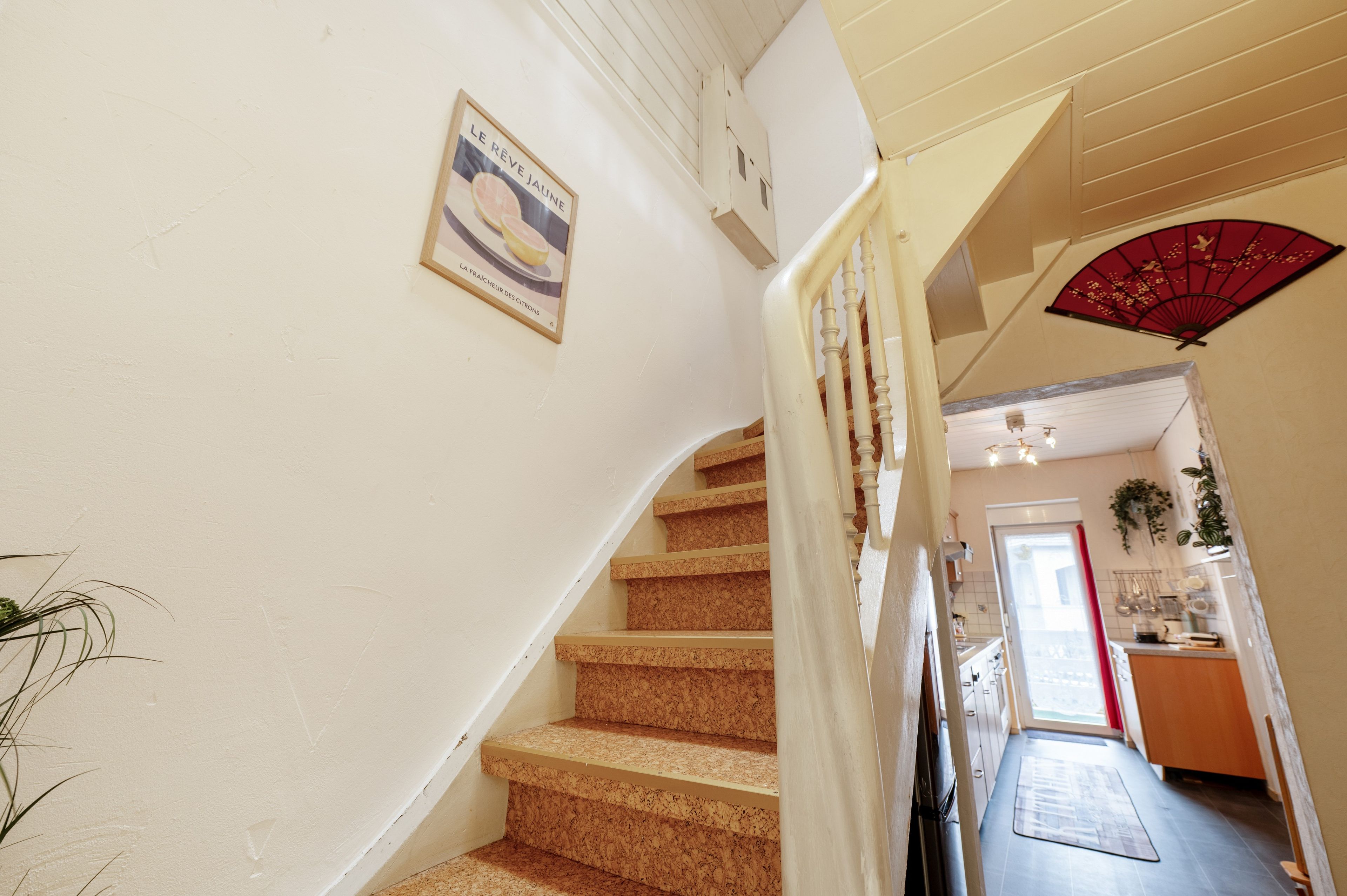 A staircase with a handrail, a wall-mounted sign, and a red fan.