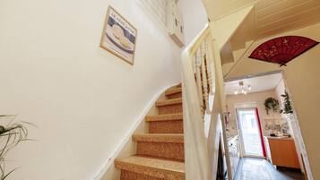 A staircase with a handrail, a wall-mounted sign, and a red fan.