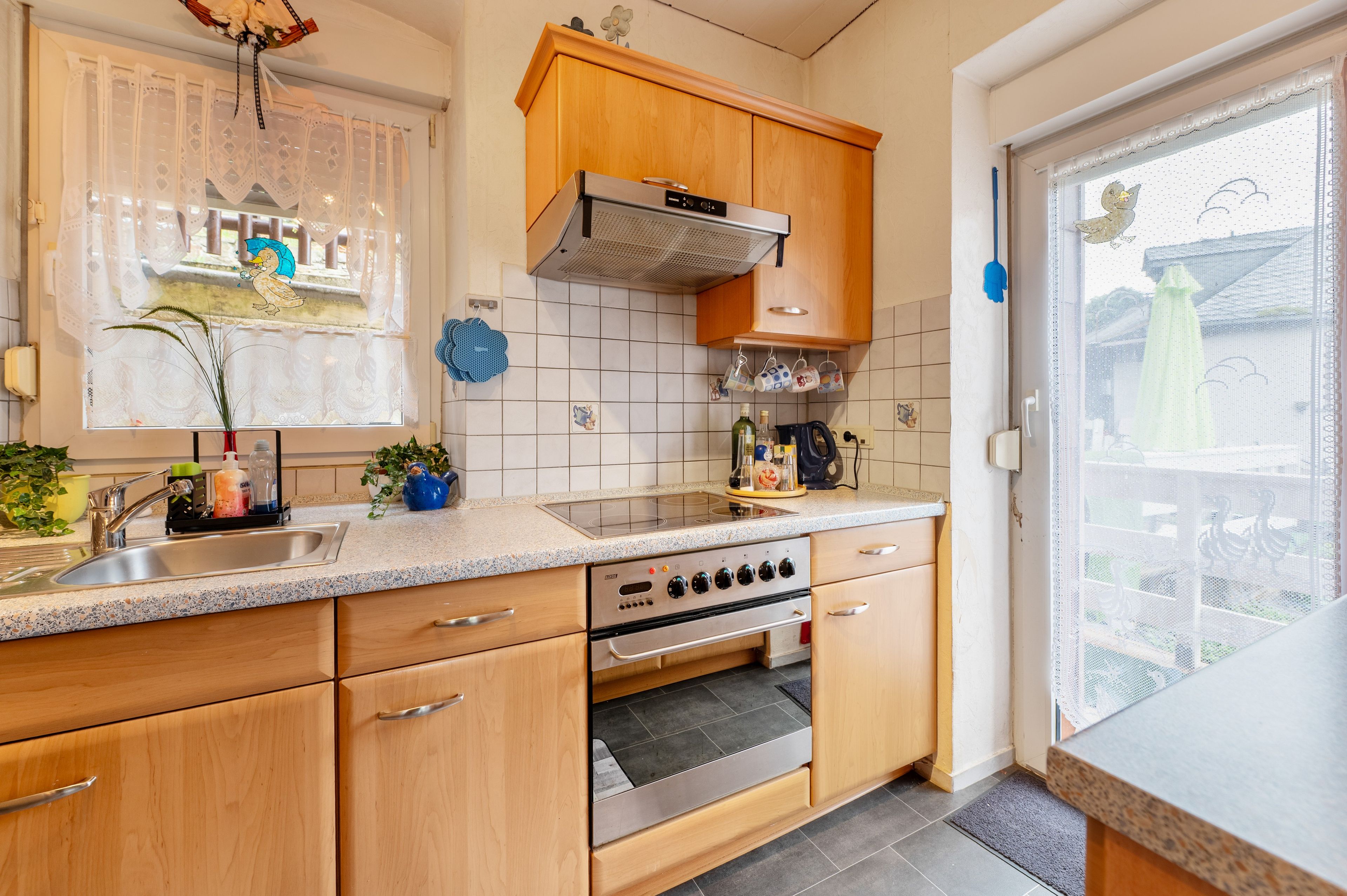 A kitchen with wooden cabinets, a stainless steel sink, and a built-in oven.
