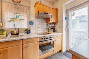 A kitchen with wooden cabinets, a stainless steel sink, and a built-in oven.