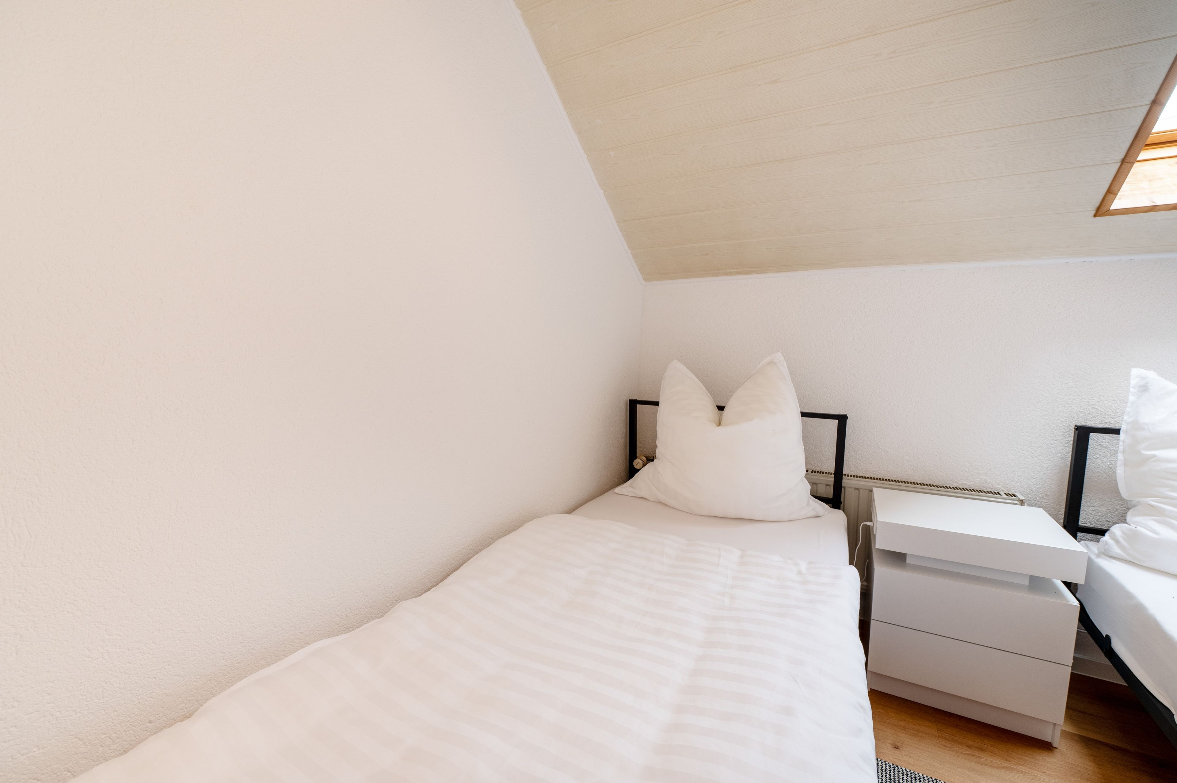 A bedroom with a bed, nightstands, and a desk.
