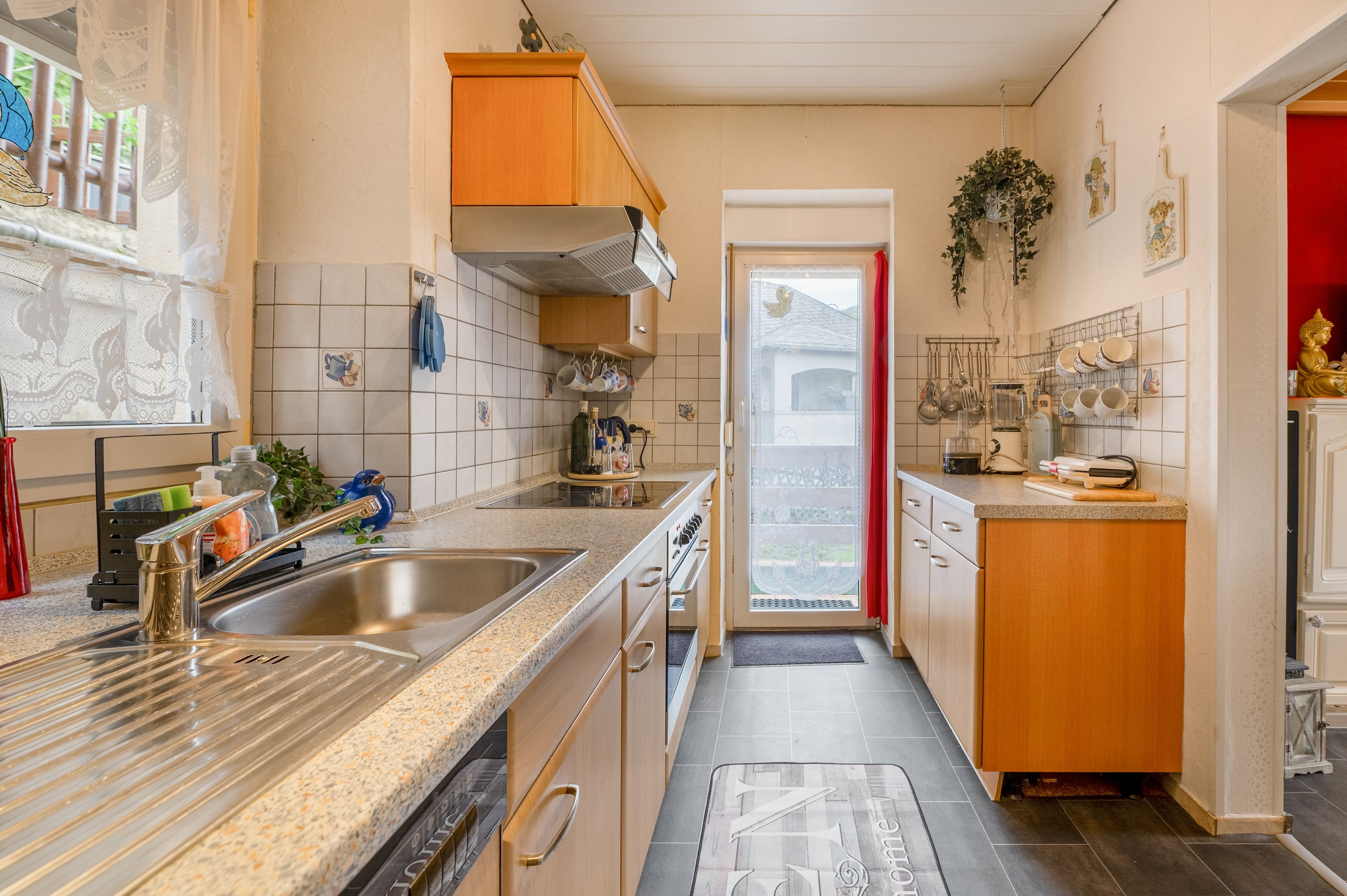 Une cuisine compacte équipée d’un évier à deux bacs, d’une cuisinière et d’un petit coin repas.