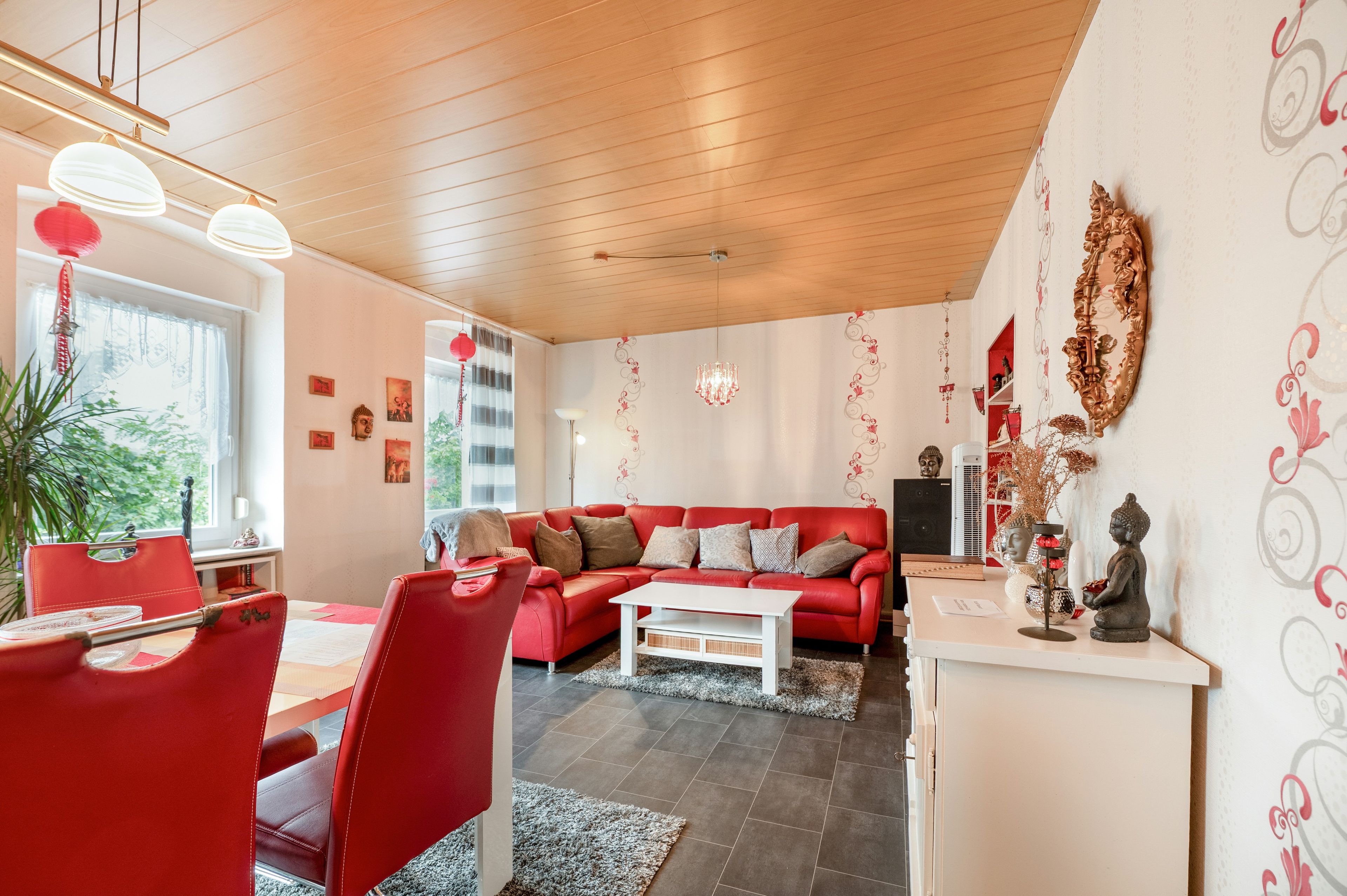Una sala de estar moderna con un sofá rojo, una mesa de centro blanca y un comedor con sillas rojas.