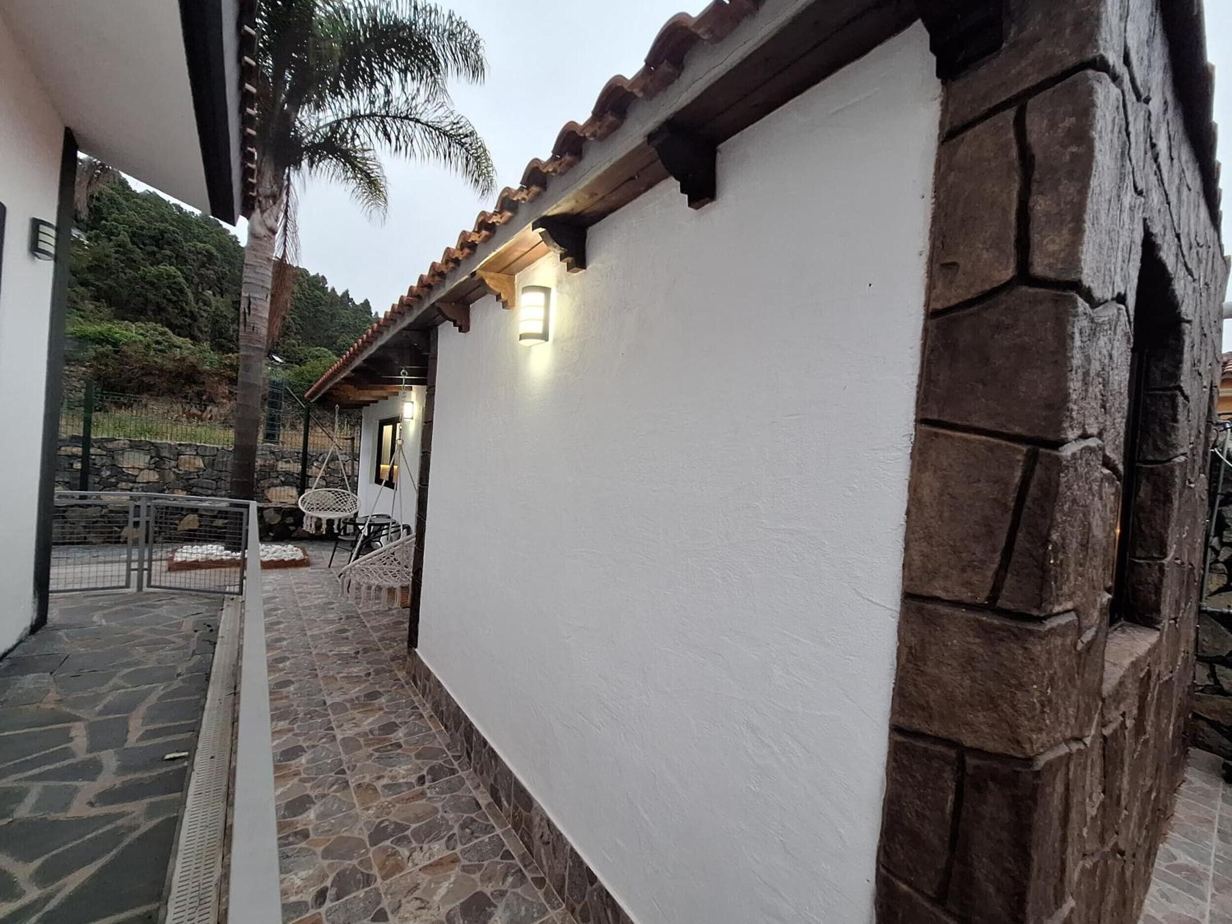 Un edificio con fachada blanca y detalles de piedra, una pared de piedra y una silla colgante.