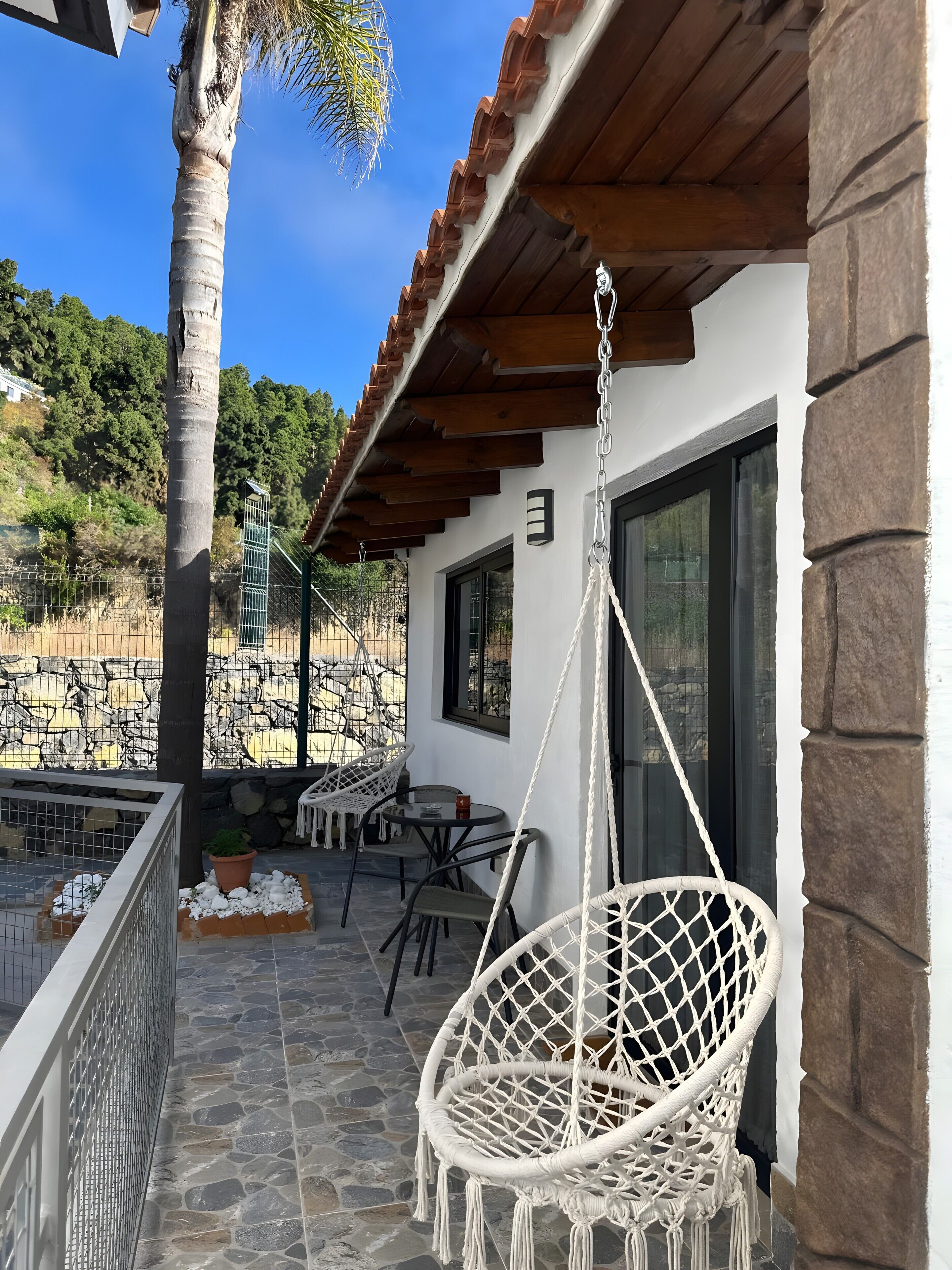Un patio con una poltrona a dondolo, pavimento in pietra e vista su un paesaggio montuoso.