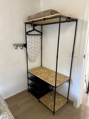 Una cama litera con estante superior y un perchero de pared.