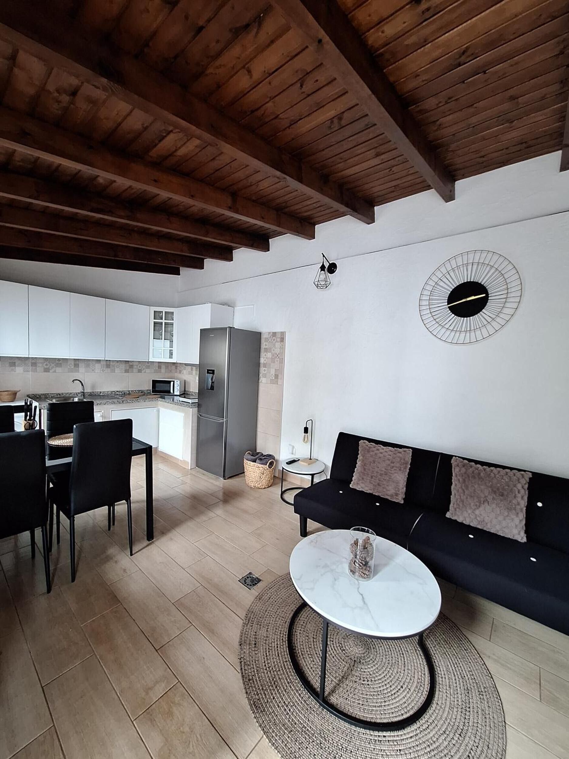 Un espacio habitable moderno con comedor, cocina y un sofá con cojines.