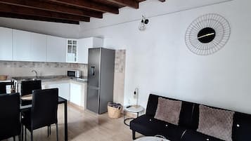 Un espacio habitable moderno con comedor, cocina y un sofá con cojines.