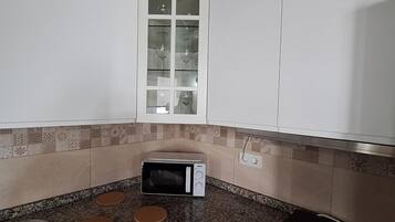 Cafetera o tetera, frigorífico, microondas y placa de cocina