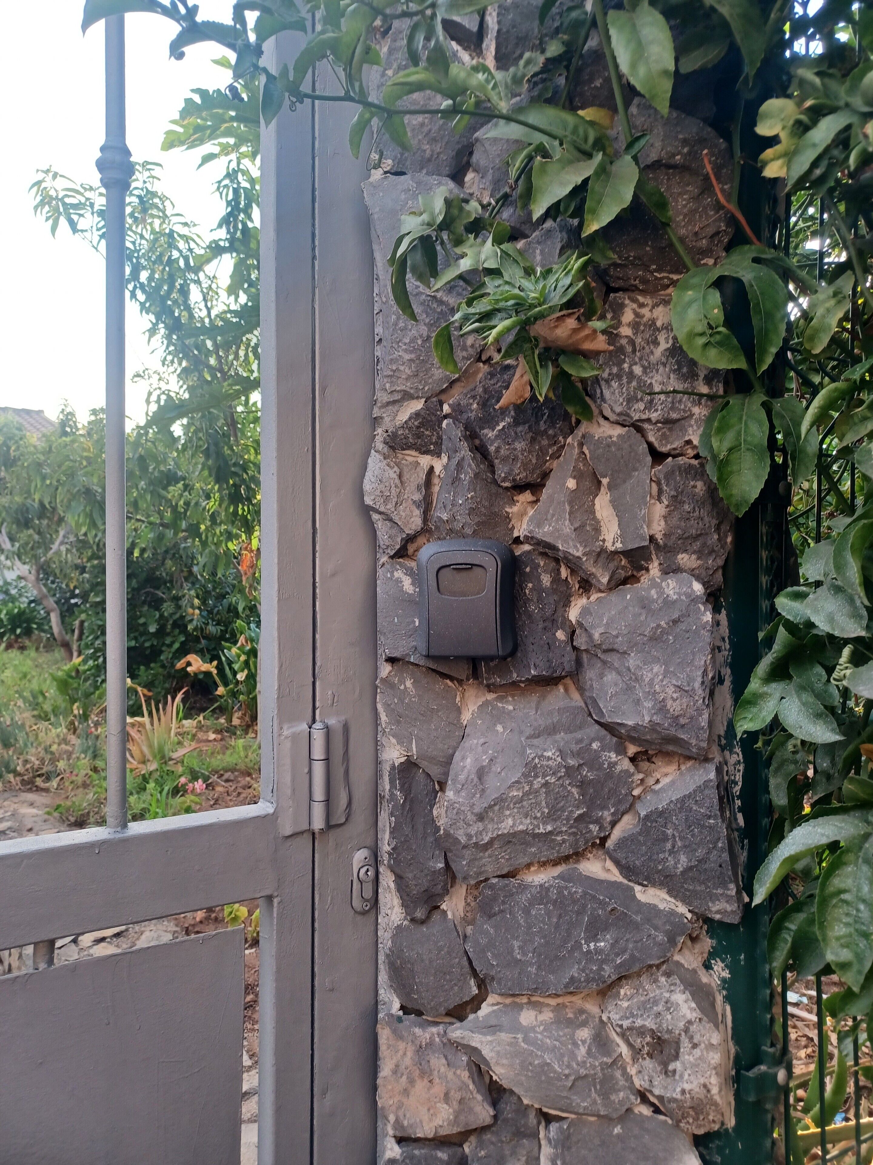 Un muro de piedra con una reja de metal y un sistema de seguridad.