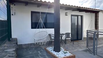 A patio area with stone flooring, a hanging chair, a table, and a tree.