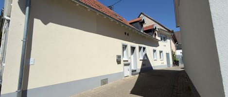 A narrow street with buildings on either side, a clear sky, and a paved road.