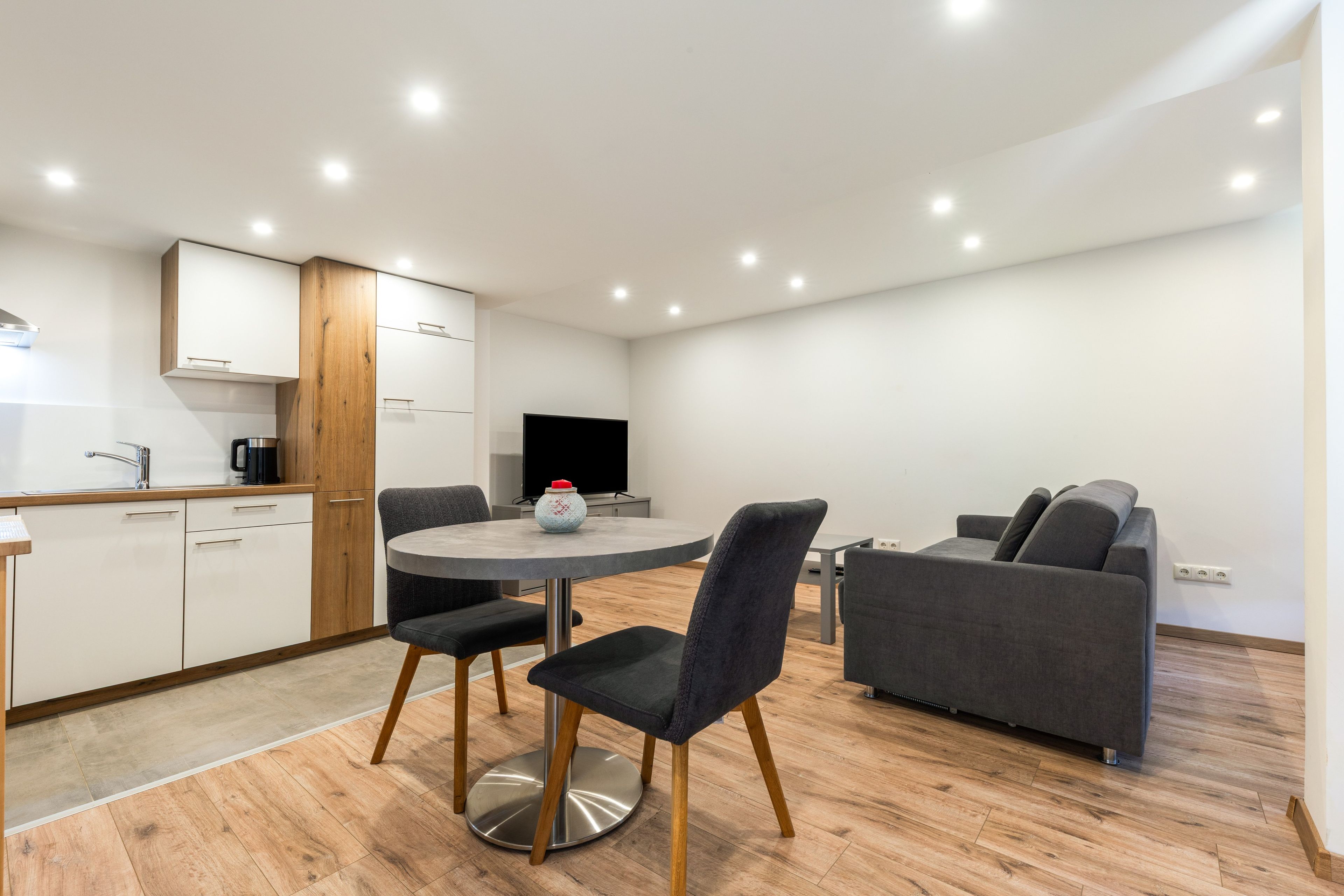 A modern kitchen with white cabinets, a wooden accent wall, and a built-in oven.
