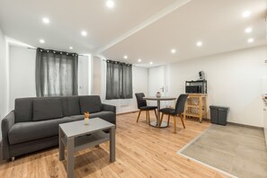 A modern living room with a grey sofa, a small table, and a dining area with two chairs. - Rheinhessen Retreat with Wi-Fi & Air Conditioning in Central Gau-Odernheim (Gau-Odernheim)