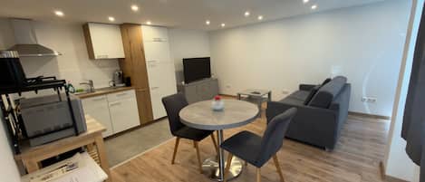 Un espacio habitable compacto con kitchenette, comedor y zona de estar.