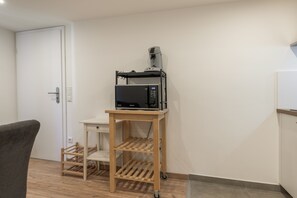 A room with a microwave on a wooden cart, a door, and a chair. - Rheinhessen Retreat with Wi-Fi & Air Conditioning in Central Gau-Odernheim (Gau-Odernheim)