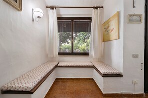Ein Eckzimmer mit Fenster, einer Wandleuchte, einem Gemälde und einer Steckdose.