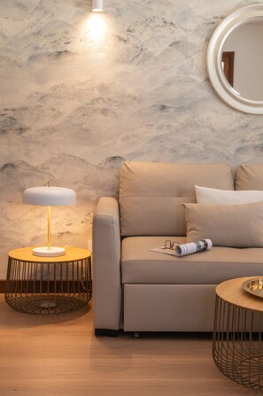 A modern living room with a sofa, a round side table, a floor lamp, and a round mirror on the wall. - Casa Ínima Holiday Home with Mountain View, Wi-Fi, and Air Conditioning (Playa Blanca)