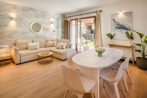 Ein modernes Wohnzimmer mit einem beigefarbenen Sofa, einem runden Couchtisch und einem Esstisch mit Stühlen.