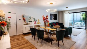 Et moderne hotelværelse med spiseplads, en sofasæt, et stort vindue med udsigt og et spejl på væggen.