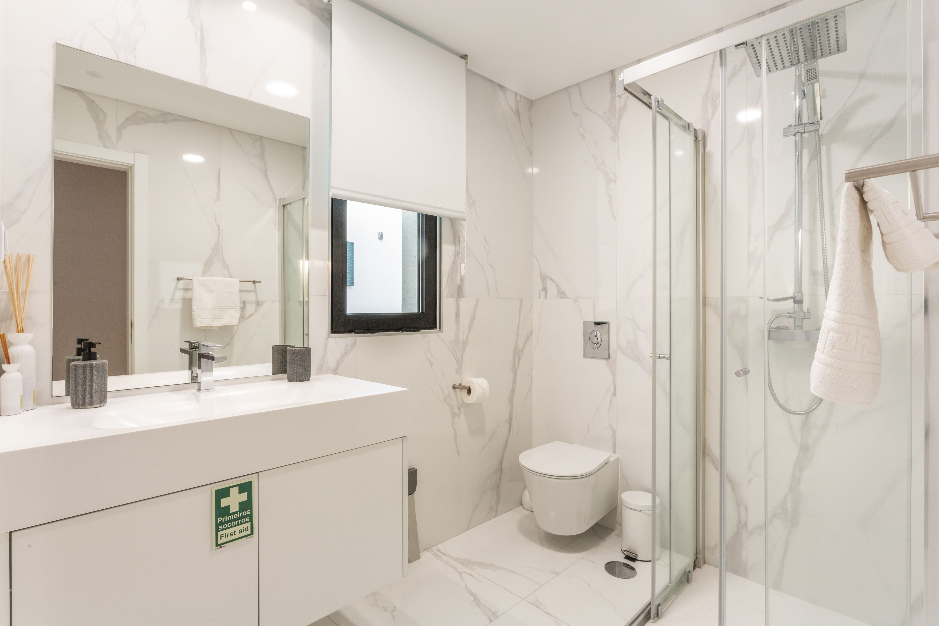 A modern bathroom with a glass shower enclosure, a white sink with a mirror, and a toilet.
