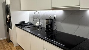 Et moderne køkken med hvide skabe, en sort bordplade og en rustfri stålvask.