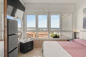 Een slaapkamer met uitzicht op de stad, een bed, een dressoir en een ventilator.