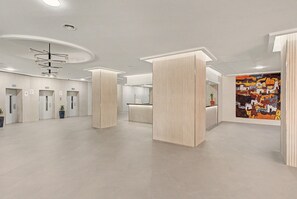 En rummelig lobby med receptionsdisk, et stort abstrakt maleri og et moderne loftdesign.