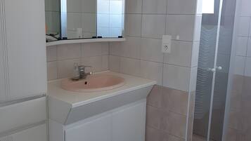 A bathroom with a sink, mirror, and shower.