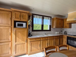 Une cuisine avec des meubles de rangement en bois, un four à micro-ondes, un évier et une cuisinière.