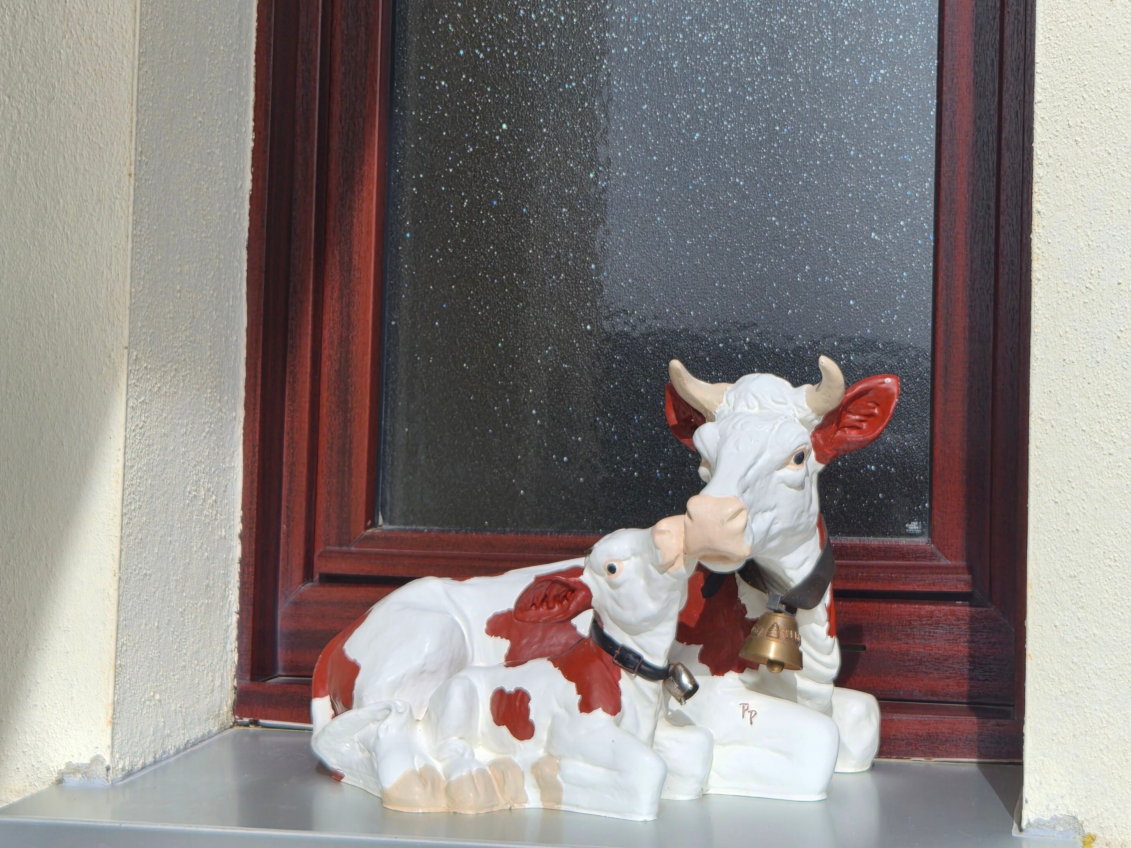 Une figurine de vache allongée sur une étagère.