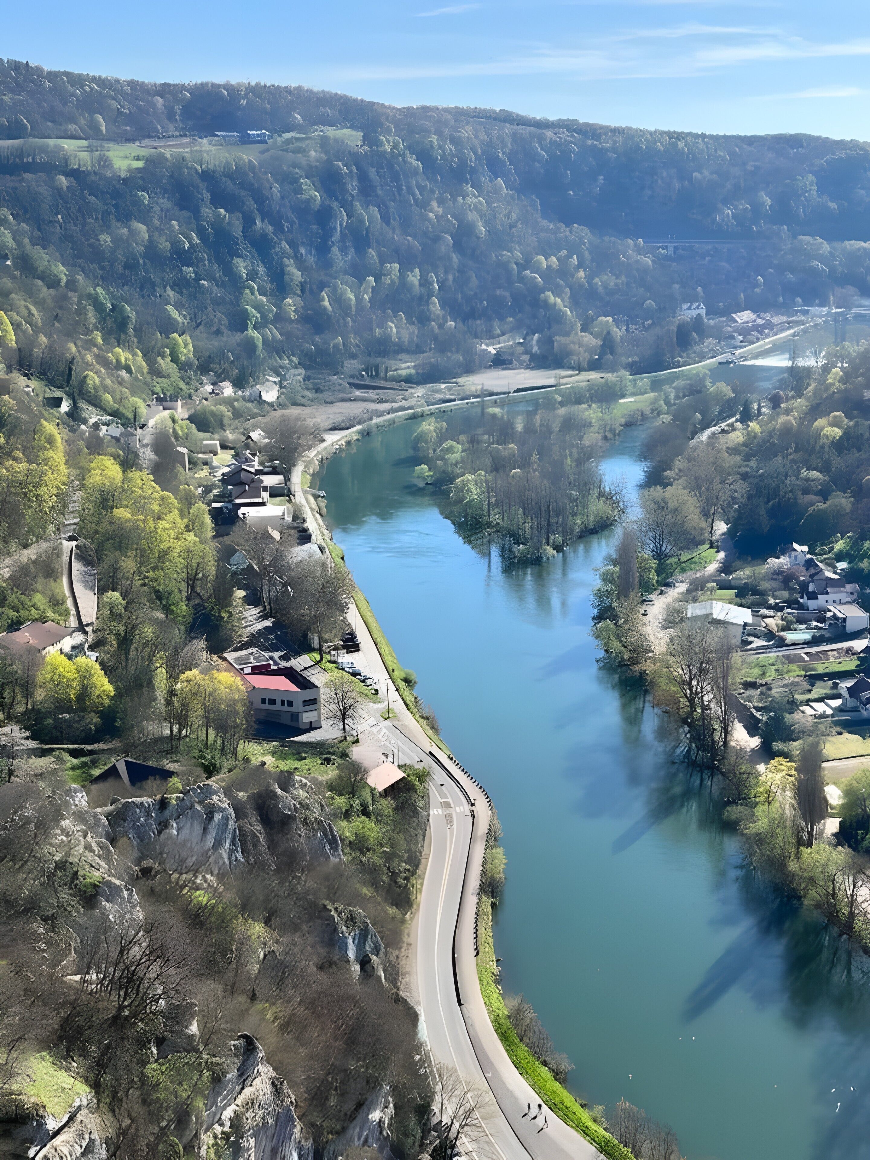 Une rivière traversée par un pont, entourée de verdure et de bâtiments.