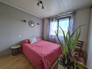 A bedroom with a bed, a round mirror, a small round table, and a large plant. - Holiday Home 'Gîte À La Campagne' with Private Terrace, Private Garden and Wi-Fi (Ouvans)