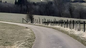 A rural road curving through a landscape with a church and open fields in the distance.